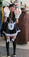 Woman in maid outfit, wearing giant cat paws and cat ears.