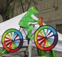 Paper scultupre of frog on bicycle with rainbow-spoke wheels